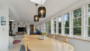 A spacious dining area with a large wooden table, chairs, and pendant lighting. - Charming cottage close to the beach (Glesborg)