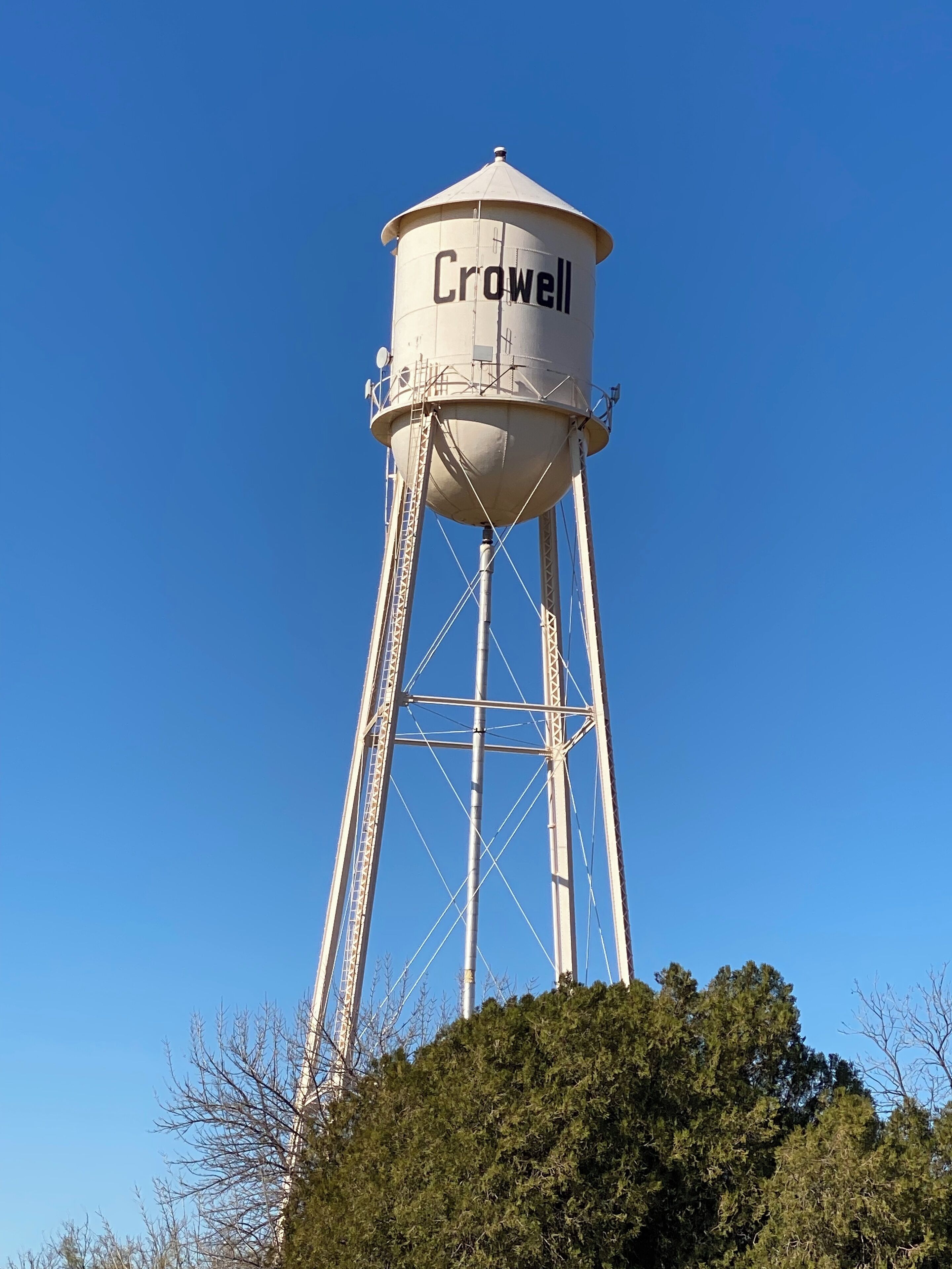 Un torre de agua con la leyenda 'Crowell' y un cielo azul despejado al fondo.