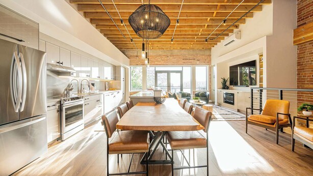 A modern kitchen with stainless steel appliances, a wooden dining table, and a large window. - Historic Elegance with Balcony Downtown View (Ogden)