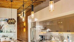 A modern kitchen with stainless steel appliances, wooden ceiling beams, and pendant lighting. - Historic Elegance with Balcony Downtown View (Ogden)