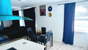 A modern kitchen with a black stove, white cabinets, and a blue ceiling light. - Serene 3-bedroom house with AC in Fort Lauderdale (Fort Lauderdale)