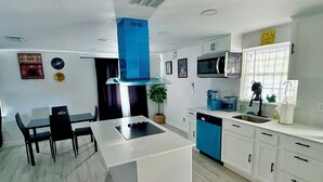 A modern kitchen with white cabinets, a blue dishwasher, and a central island with a black countertop. - Serene 3-bedroom house with AC in Fort Lauderdale (Fort Lauderdale)