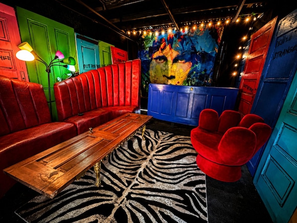 A room with a red leather couch, a wooden coffee table, and a zebra-patterned rug.