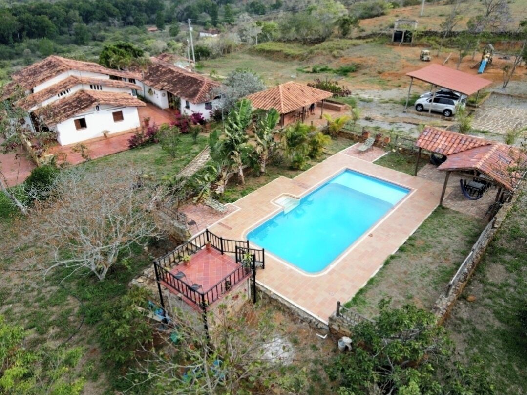 Vista aérea de uma área residencial com piscina, várias casas e um carro.