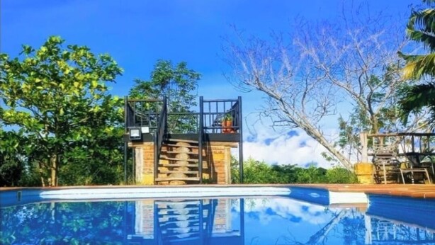 A clear blue swimming pool with a wooden deck and a metal staircase leading to a platform. - San Rafael del Campo Barichara (Barichara)