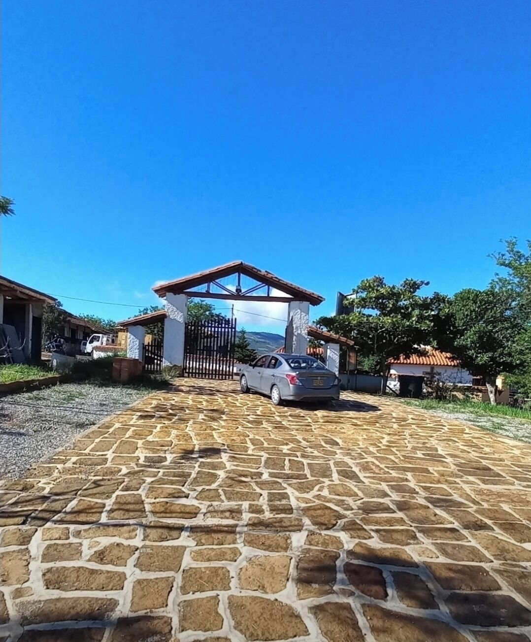 A paved driveway leading to a gated entrance with a car parked nearby.