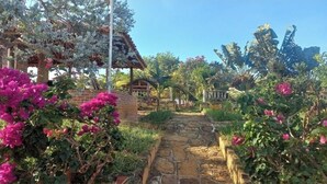 A stone pathway leading to a rustic wooden structure with a pergola covered in white flowers. - San Rafael del Campo Barichara (Barichara)
