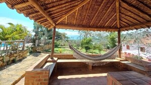 A covered outdoor seating area with a hammock, stone walls, and a view of the landscape. - San Rafael del Campo Barichara (Barichara)