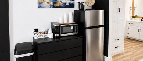 A modern kitchen with a coffee bar, microwave, and stainless steel refrigerator.