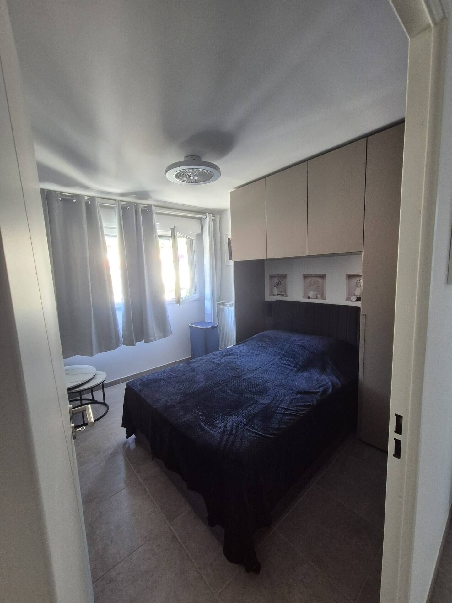 Una camera da letto con un letto, un tavolino e una finestra con tende.