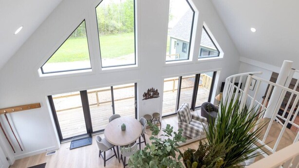 A spacious loft with large windows, a wooden deck, and a cozy seating area.