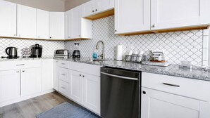 A modern kitchen with white cabinets, a granite countertop, and a dishwasher.