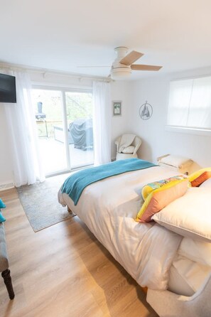 Een slaapkamer met een bed, een plafondventilator, een raam en uitzicht op het exterieur.