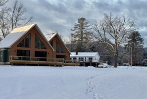 Une cabane dotée d’une grande terrasse et d’un espace abrité, entourée de neige.