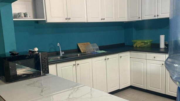 A kitchen with white cabinets, a marble countertop, and a blue accent wall.