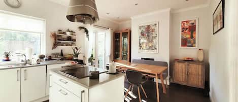 A modern kitchen with white cabinetry, a central island, and a dining area with a wooden table and chairs.