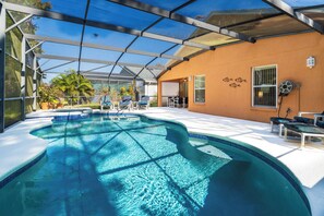 A swimming pool with a glass enclosure, surrounded by lounge chairs and a covered patio area. - The Dreamers Hideaway @ Sandy Ridge - Your luxury home from home! (Davenport)