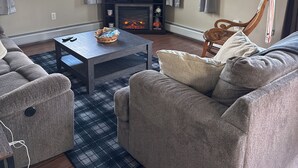 A living room with a fireplace, sofa, coffee table, and a TV. - Private 2 bedroom lofted garage getaway. (Newport Center)