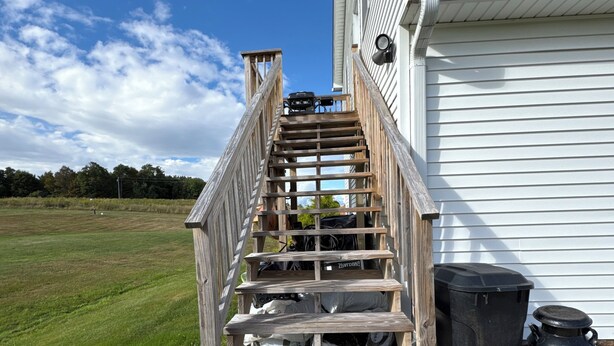 A wooden staircase leading to a white building with a metal door. - Private 2 bedroom lofted garage getaway. (Newport Center)