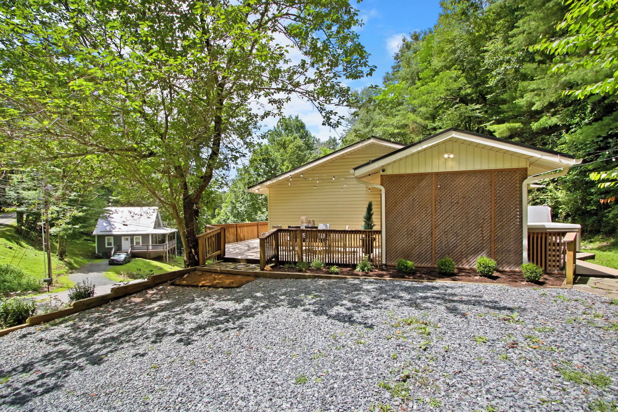 A two-story house with a covered porch, a fenced yard, and a gravel driveway.