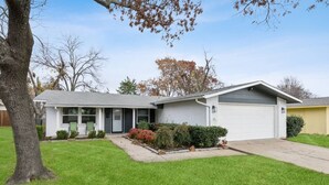 Une maison de plain-pied avec un porche à l’avant, un garage et une pelouse bien entretenue.