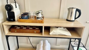 A wooden shelf with a portable radio, a coffee pot, a chessboard, and a trash bin. - The Cabin at No. 12 (Exeter)