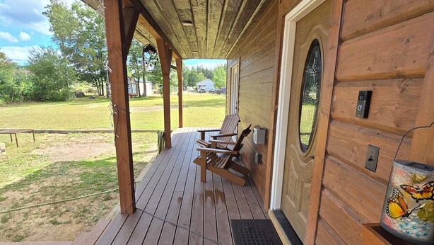 Eine Holzterrasse mit überdachter Veranda, einer Bank und einem dekorativen Element zum Schmetterling-Thema.