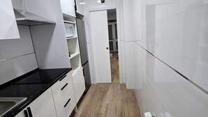 Una cocina moderna con armarios blancos, encimera negra y suelo de madera.