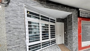 A building entrance with a stone facade, a metal gate, and a tiled floor. - Apartment in Southern Madrid for Groups/Families (Leganes)