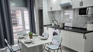 A modern kitchen with white cabinets, a black countertop, and a stainless steel refrigerator. - Apartment in Southern Madrid for Groups/Families (Leganes)