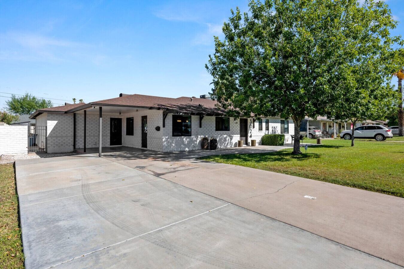 A single-story house with a front porch, a driveway, and a tree in front.