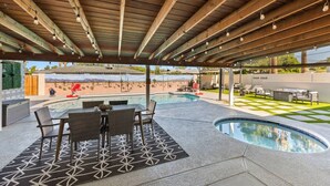 A covered outdoor area with a pool, seating, and a view of a desert landscape.