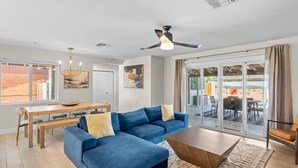 A modern living room with a blue sectional sofa, a wooden coffee table, and a dining area with a wooden table and chairs.