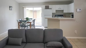 Un salon moderne avec un canapé gris et un coin repas comprenant une table et des chaises.