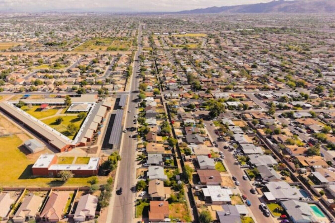An aerial view of a residential area with houses, roads, and a large building complex.
