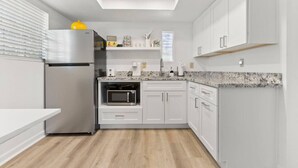 A modern kitchen with white cabinetry, a built-in microwave, and a stainless steel refrigerator.