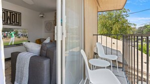 A balcony with a sofa, two chairs, and a TV displaying a golf game.