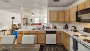 A modern kitchen with wooden cabinets, a dishwasher, a stove, and a microwave. - Simple and Sweet 3 Bed 2 Bath (Mesquite)