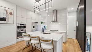 A modern kitchen with white cabinetry, stainless steel appliances, and a central island with bar stools.