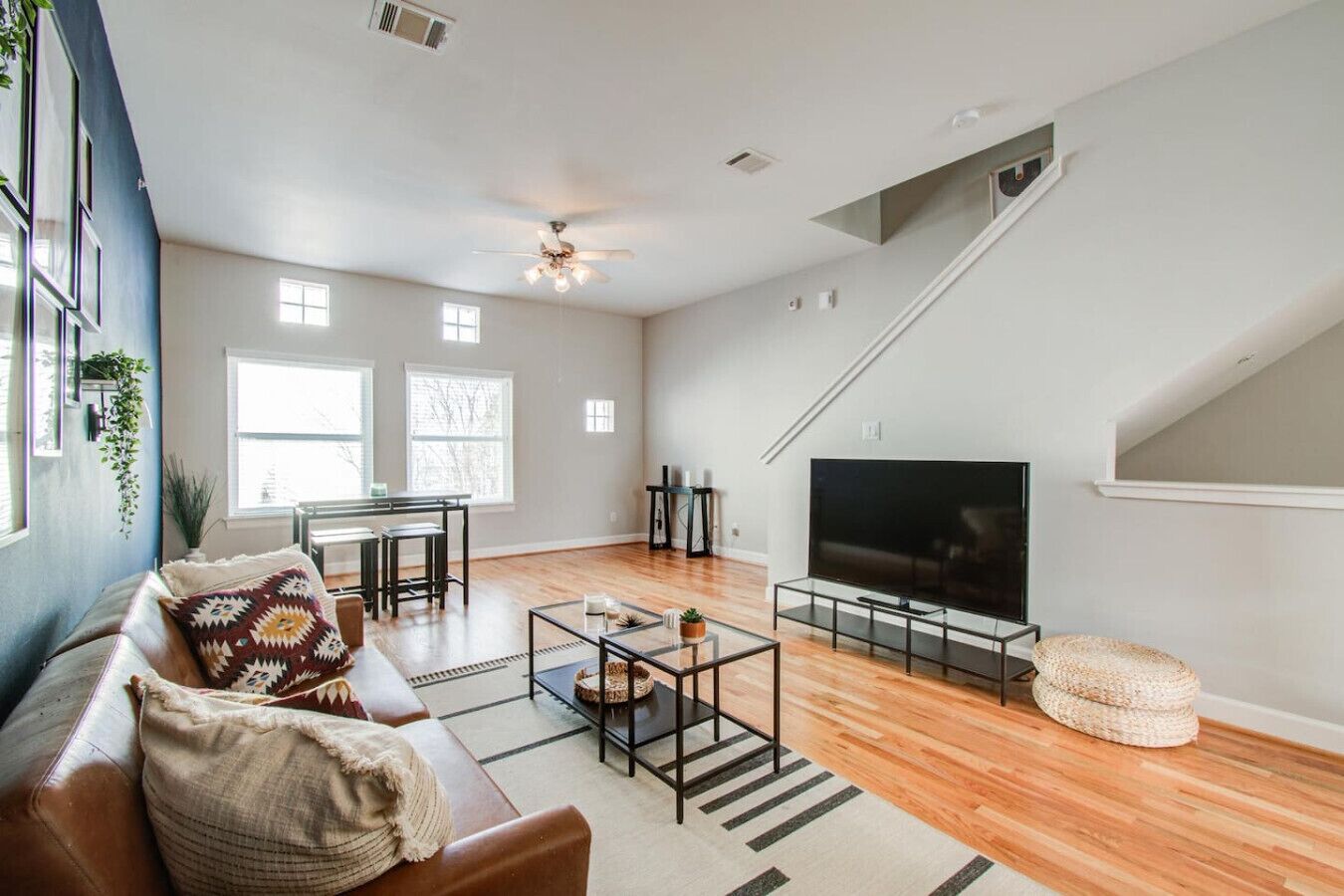 A spacious living room with a large TV, a sofa, a coffee table, and a staircase.