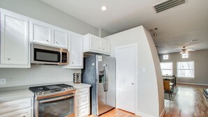 A modern kitchen with white cabinetry, stainless steel appliances, and hardwood flooring.
