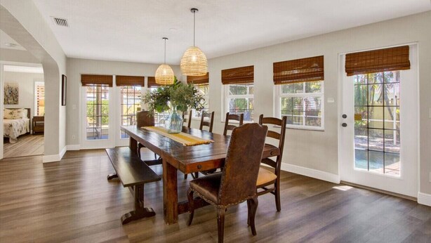 A spacious dining area with a wooden table and chairs, large windows with blinds, and a view of the outdoors. - Tropical Escape | Pool | Game Room | Near Beach (St. Petersburg)