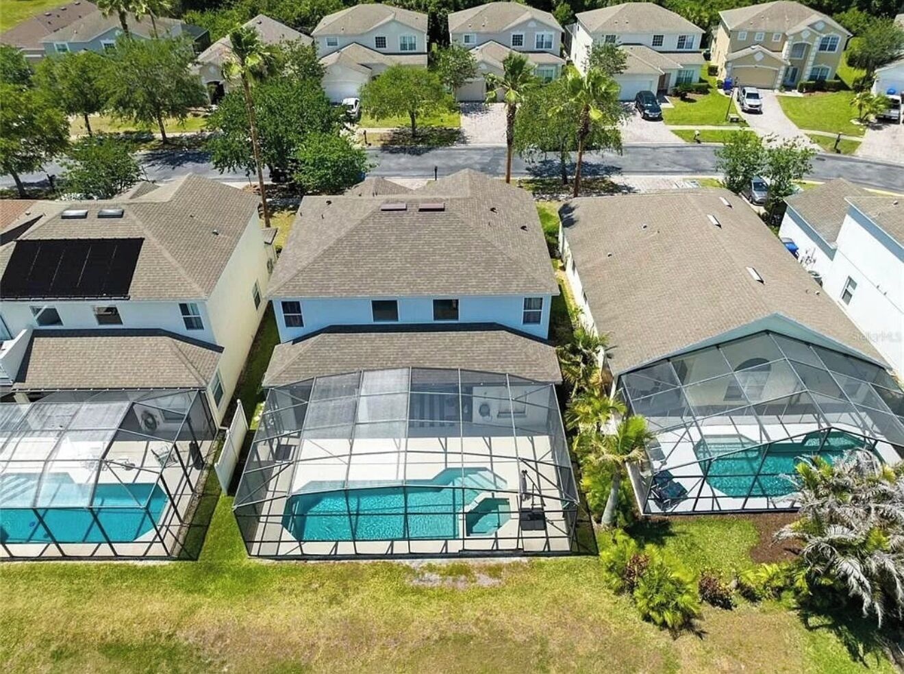 A residential area with multiple houses, each featuring a covered swimming pool.