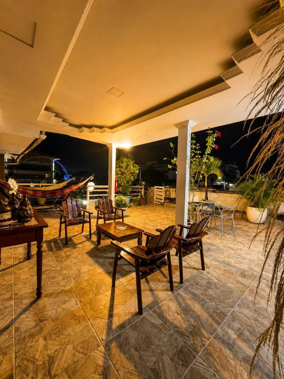 Un patio al aire libre con zona de comedor, sillas y mesas.