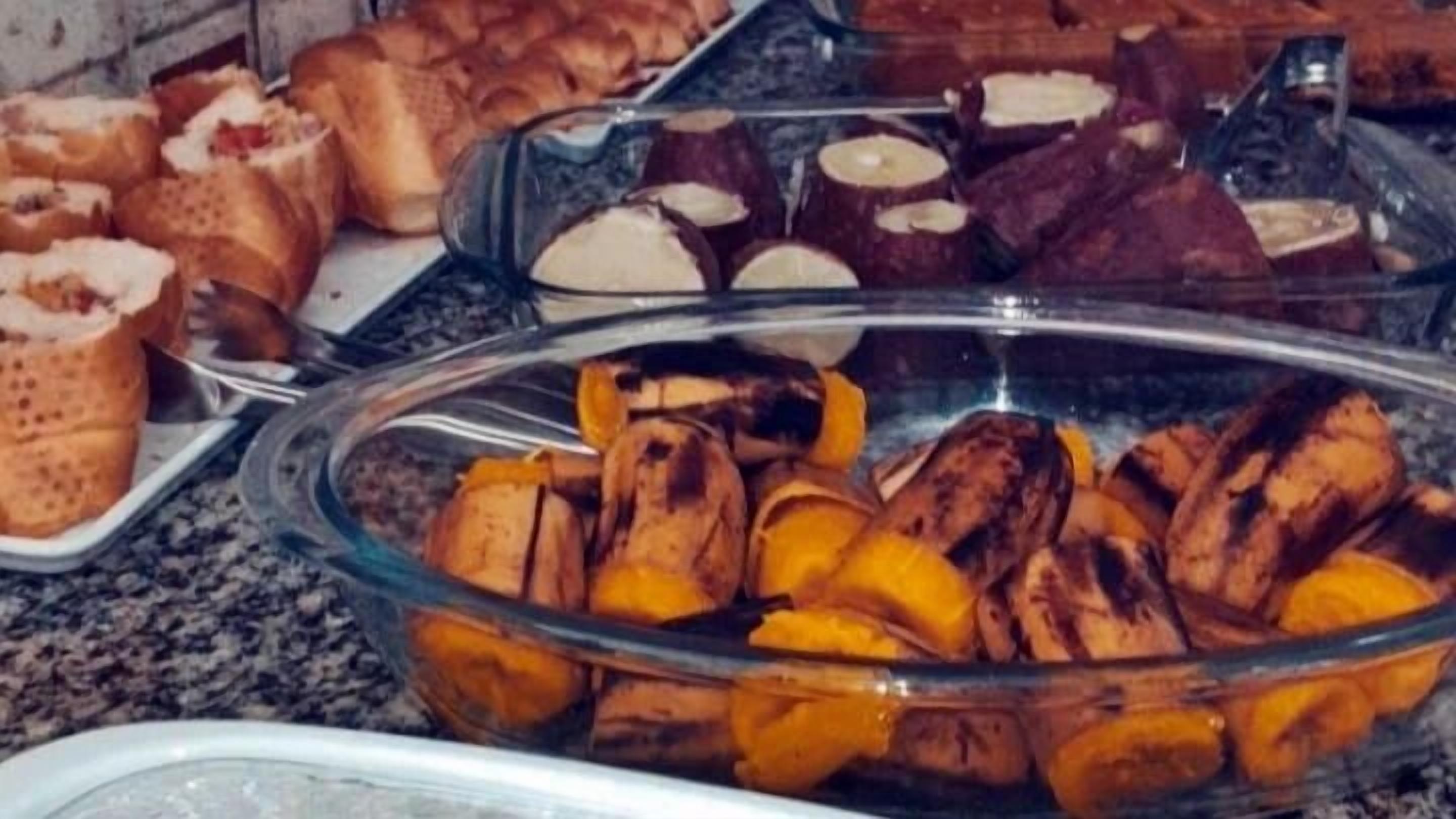 A buffet with various food items including bread, cakes, and roasted vegetables.