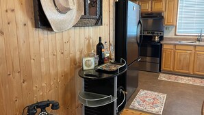 Une cuisine avec des meubles de rangement en bois, un réfrigérateur, une cuisinière et un téléphone.
