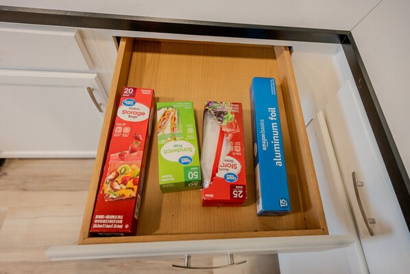 A drawer with four items: gallon storage bags, sandwich bags, aluminum foil, and a box of aluminum foil.
