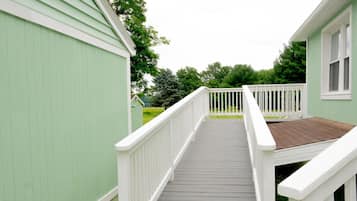 A wooden deck leading to a green building with white railings.