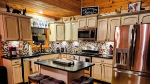 A kitchen with wooden cabinets, a stainless steel refrigerator, a microwave, and a coffee maker. - Mountain Views! Family-friendly, 4 BR + Bunkroom, NEW Hot Tub, Firepit, Gameroom (Hiawassee)