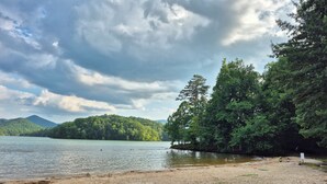 A beach with a sandy shore, calm water, and dense forested hills in the background. - Mountain Views! Family-friendly, 4 BR + Bunkroom, NEW Hot Tub, Firepit, Gameroom (Hiawassee)